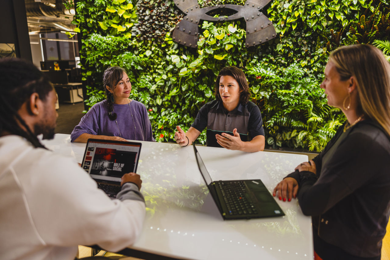 Team meeting with laptops in an outdoor green space