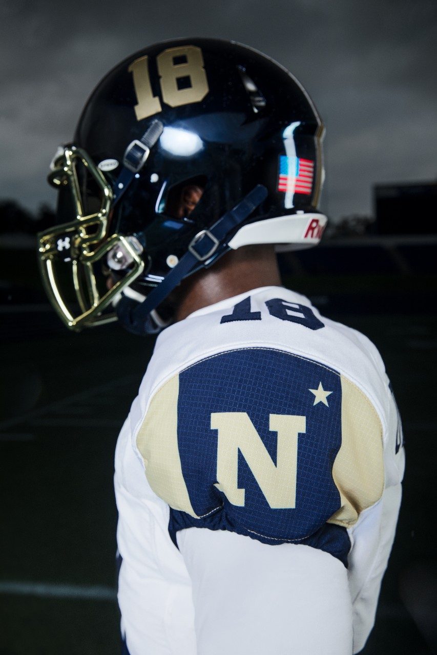 The sleeves of the jersey are navy blue in color and feature two stripes on the outside with the Navy logo in the center. This color-blocking look was inspired directly from the trim of the blanket popularly worn by Bill the Goat. 

Bill the Goat is depicted on the sides of the helmet, charging forward and wrapped in its blanket.