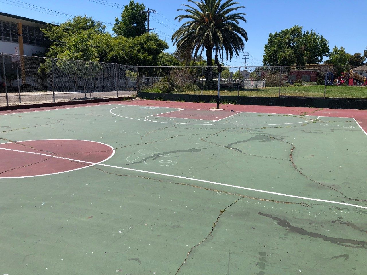 'Before' photo of the Concordia Park basketball court with missing hoop, uneven and cracked pavement.
