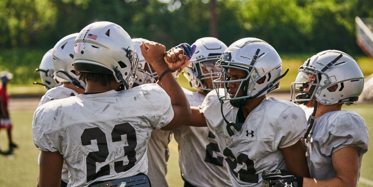 Diverse men's youth football team huddle