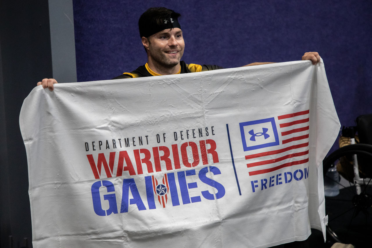 A man holding a flag that says "Warrior Games"