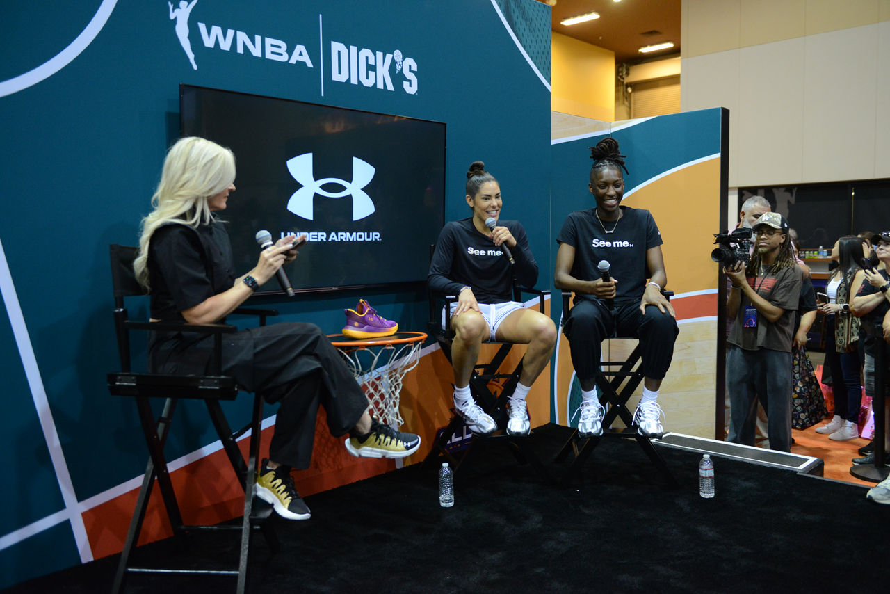 three women on stage holding mircophones addressing a crowd