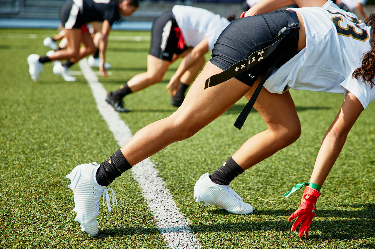 Photo of girl on football field wearing Under Armour Blur football cleats and gloves